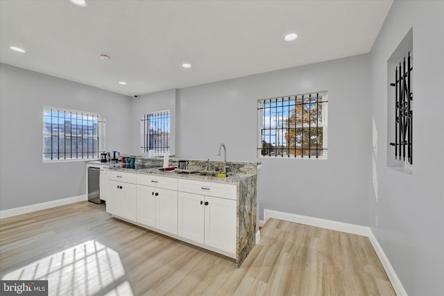 kitchen with white cabinetry, a wealth of natural light, light stone counters, and light wood-type flooring