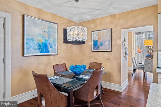 dining area with dark wood-type flooring and a notable chandelier