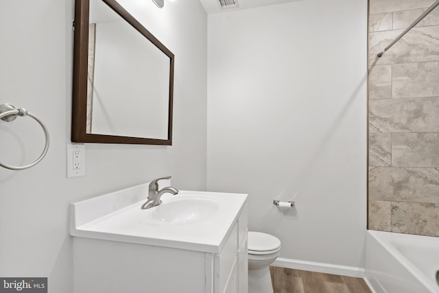 full bathroom with wood-type flooring, tiled shower / bath combo, toilet, and vanity