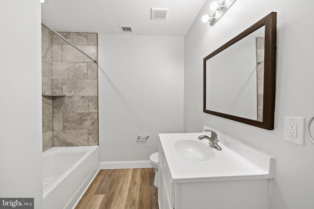 full bathroom featuring tiled shower / bath combo, vanity, hardwood / wood-style flooring, and toilet