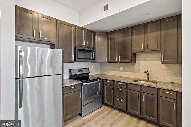 kitchen with light hardwood / wood-style flooring, sink, light stone counters, and stainless steel appliances