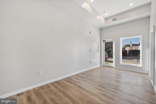 spare room with light hardwood / wood-style floors and a towering ceiling