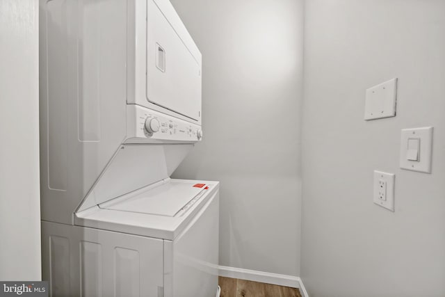 washroom with wood-type flooring and stacked washer / drying machine