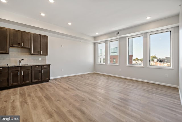 unfurnished living room featuring sink and light hardwood / wood-style floors