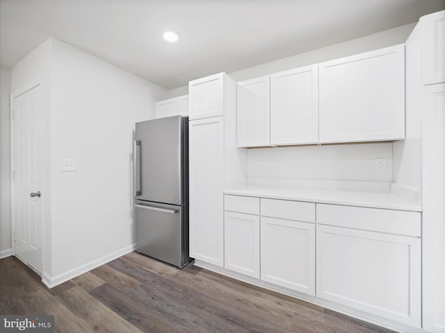 kitchen featuring white cabinets, dark wood-type flooring, and stainless steel refrigerator