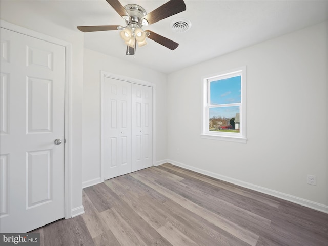 unfurnished bedroom featuring ceiling fan, light wood-type flooring, and a closet