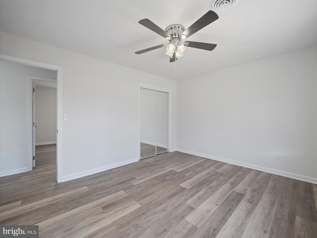 unfurnished bedroom featuring a closet, light hardwood / wood-style floors, and ceiling fan