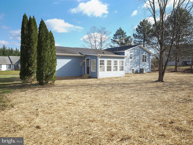 back of property featuring central AC unit and a lawn