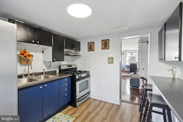 kitchen featuring stainless steel gas range oven, blue cabinetry, sink, and light hardwood / wood-style floors