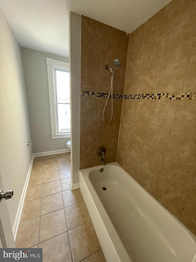 bathroom featuring toilet, tiled shower / bath, and tile patterned floors