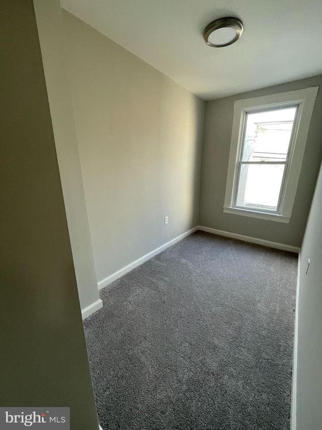 unfurnished room featuring dark carpet