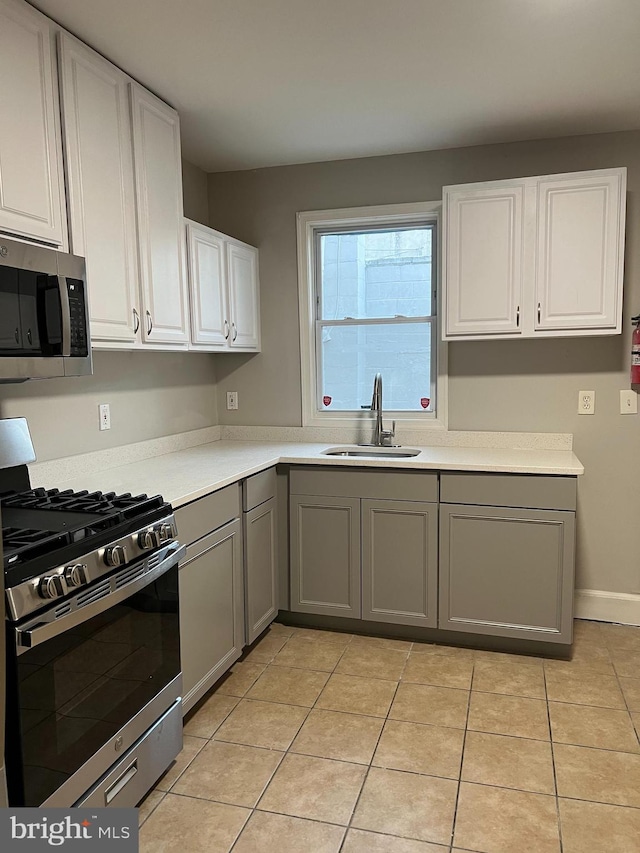 kitchen featuring stainless steel appliances, gray cabinetry, sink, and light tile patterned floors