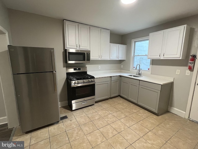 kitchen with sink, gray cabinets, light tile patterned floors, and appliances with stainless steel finishes