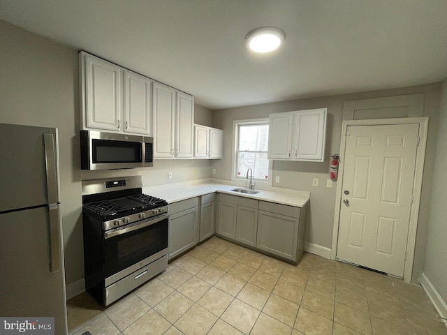 kitchen with stainless steel appliances, white cabinetry, sink, light tile patterned floors, and gray cabinetry