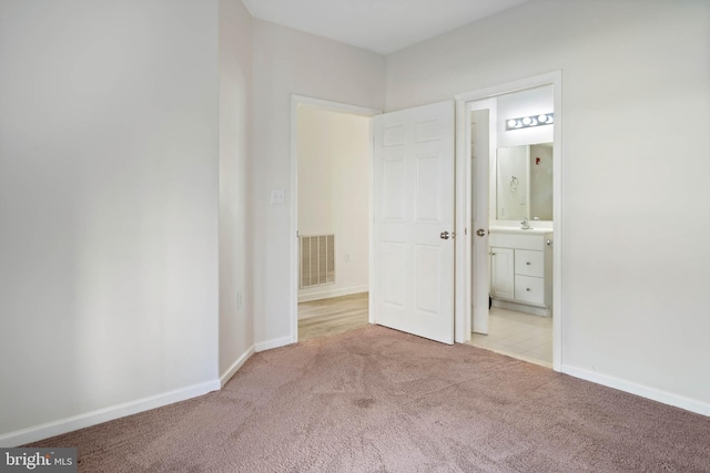 unfurnished bedroom featuring ensuite bathroom and light colored carpet