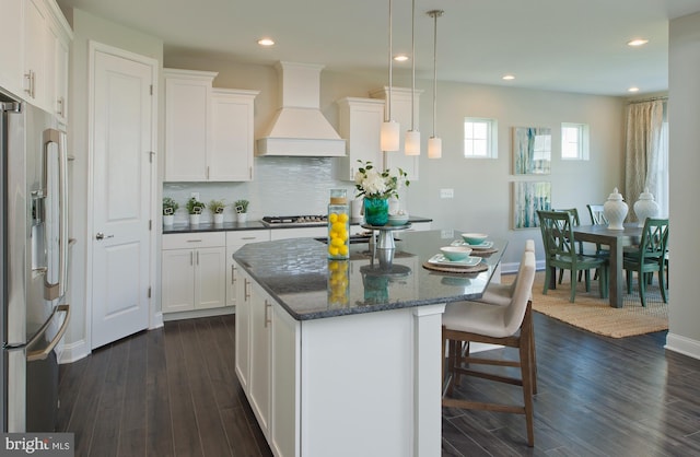 kitchen featuring white cabinetry, appliances with stainless steel finishes, custom range hood, dark hardwood / wood-style flooring, and a center island