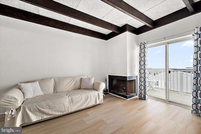 living room with a multi sided fireplace, light hardwood / wood-style floors, and beam ceiling