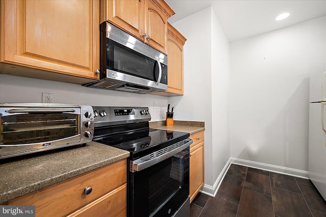 kitchen featuring stainless steel appliances, dark wood-type flooring, and dark stone countertops