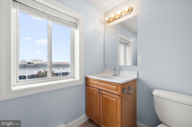 bathroom with a wealth of natural light, tile patterned floors, vanity, and toilet