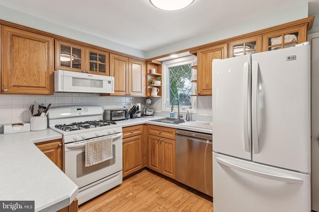 kitchen with backsplash, sink, white appliances, and light wood-type flooring