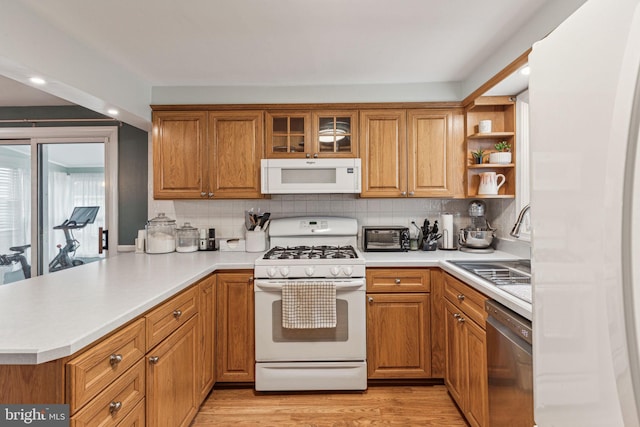 kitchen featuring backsplash, white appliances, kitchen peninsula, and light hardwood / wood-style flooring