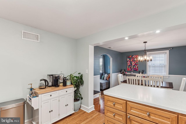 kitchen featuring an inviting chandelier, white cabinets, butcher block countertops, decorative light fixtures, and light hardwood / wood-style floors