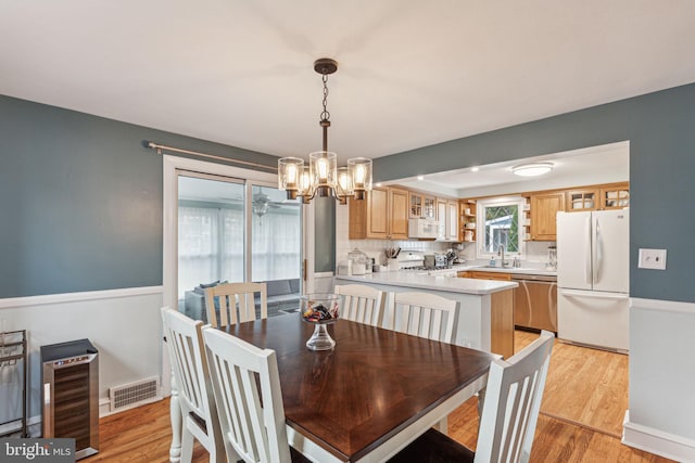 dining area with a chandelier, wine cooler, light hardwood / wood-style flooring, and sink