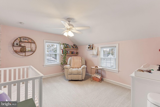 carpeted bedroom with vaulted ceiling, a nursery area, and ceiling fan