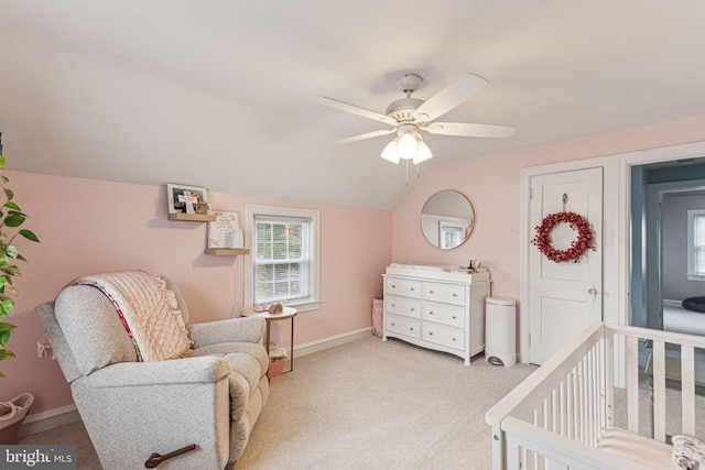 carpeted bedroom with ceiling fan, vaulted ceiling, and a nursery area