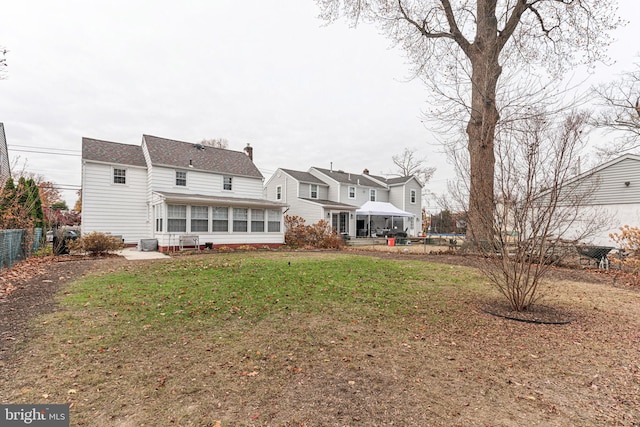 back of property with a yard and a sunroom