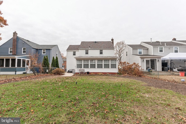 back of property featuring a lawn and a sunroom