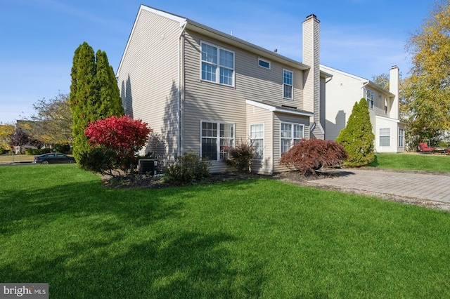 back of property featuring central air condition unit and a yard