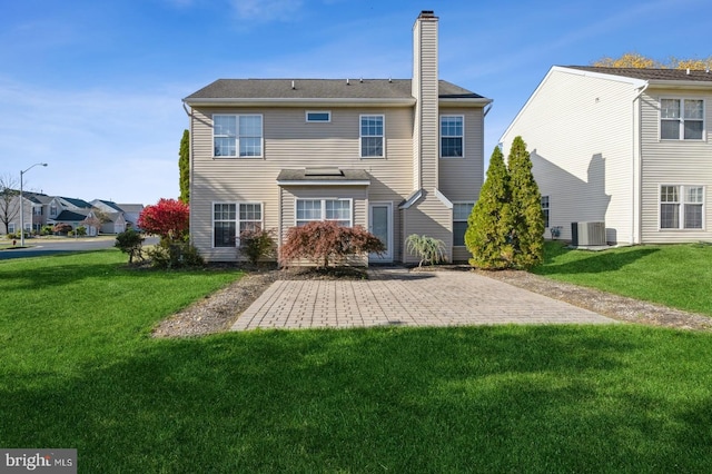 back of property with central air condition unit, a patio area, and a lawn