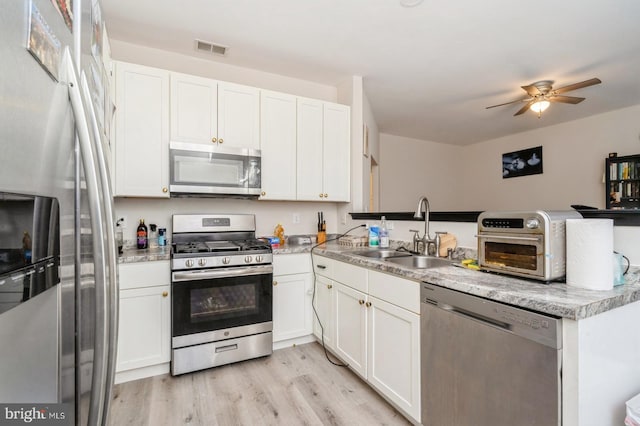 kitchen featuring sink, kitchen peninsula, appliances with stainless steel finishes, light hardwood / wood-style flooring, and white cabinets