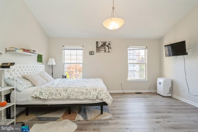 bedroom with multiple windows, vaulted ceiling, and light hardwood / wood-style floors