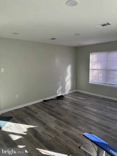 unfurnished room featuring visible vents, baseboards, and wood finished floors