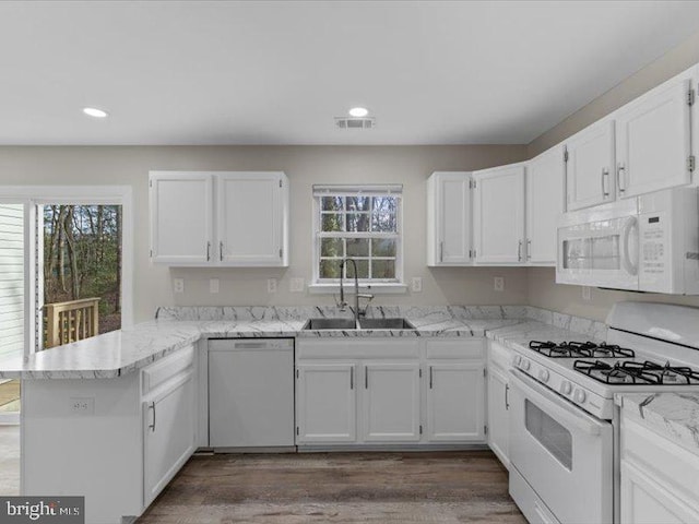 kitchen with white cabinets, a sink, white appliances, plenty of natural light, and a peninsula