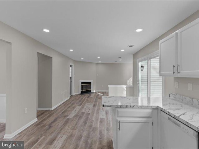 kitchen featuring recessed lighting, a glass covered fireplace, white cabinets, light wood-type flooring, and a peninsula