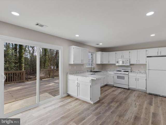 kitchen with white appliances, light wood-style flooring, visible vents, and white cabinetry