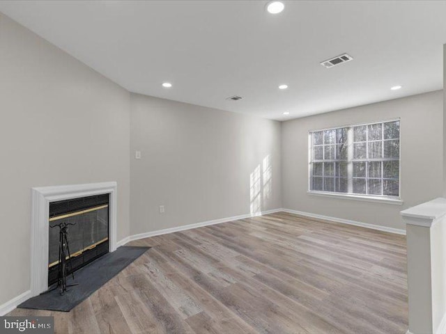 unfurnished living room with baseboards, visible vents, a fireplace with flush hearth, wood finished floors, and recessed lighting