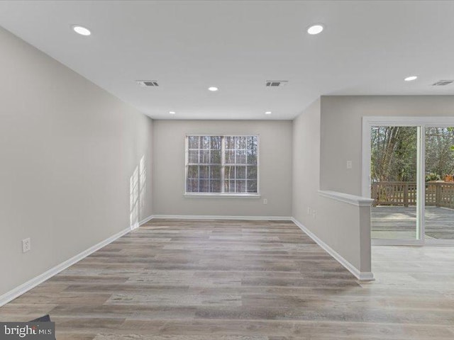 spare room featuring baseboards, wood finished floors, visible vents, and a healthy amount of sunlight