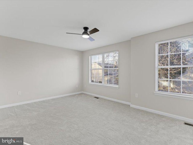 unfurnished room with carpet, visible vents, ceiling fan, and baseboards