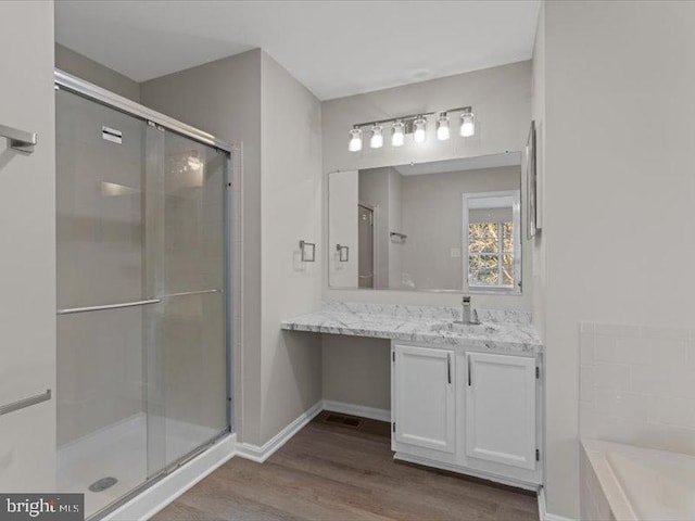 full bathroom with a stall shower, vanity, baseboards, and wood finished floors