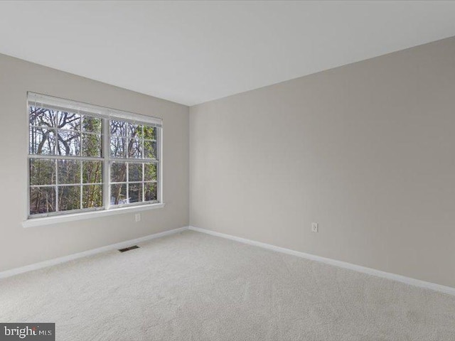 unfurnished room featuring carpet, visible vents, and baseboards