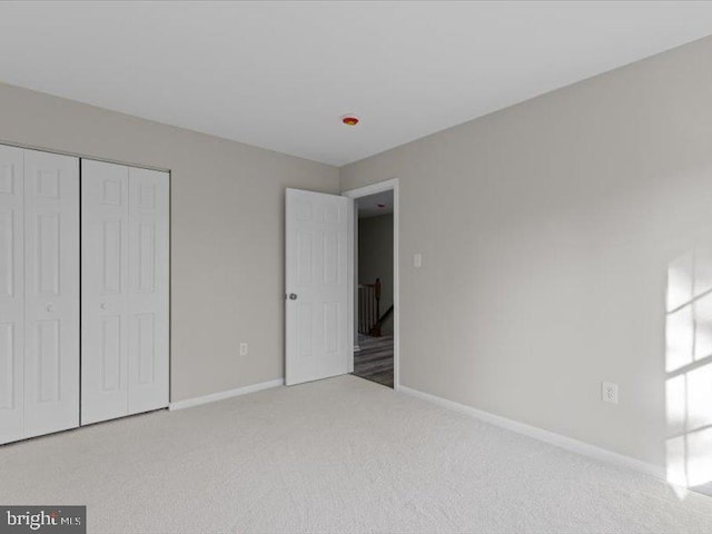 unfurnished bedroom with carpet, a closet, and baseboards