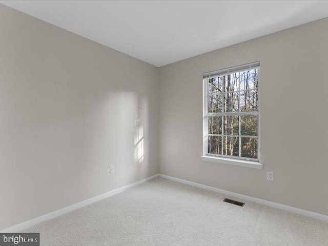 carpeted spare room with visible vents and baseboards