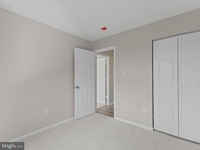 unfurnished bedroom featuring carpet floors, a closet, and baseboards