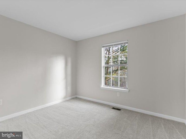 carpeted spare room featuring visible vents and baseboards