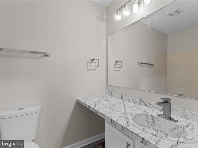 bathroom with toilet, vanity, and visible vents