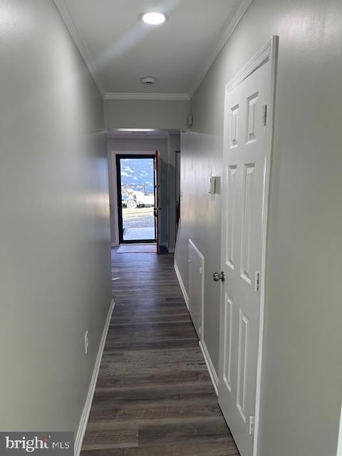 corridor with ornamental molding, dark wood-type flooring, and baseboards